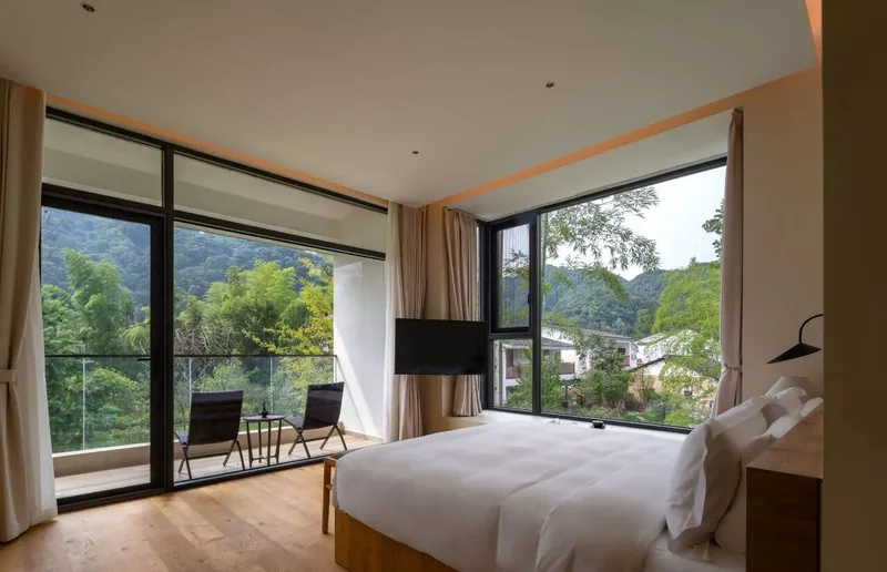 A mountain-view room and balcony overlooking greenery at WUMINGCHU Wentang Hotel